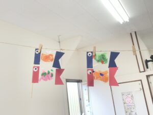 Colorful paper fish garland hanging on a string with clothespins in a classroom or hallway.