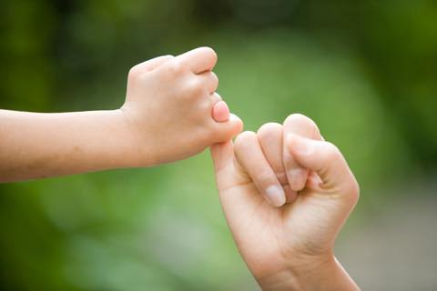 子どもと大人が指切りをしている手元