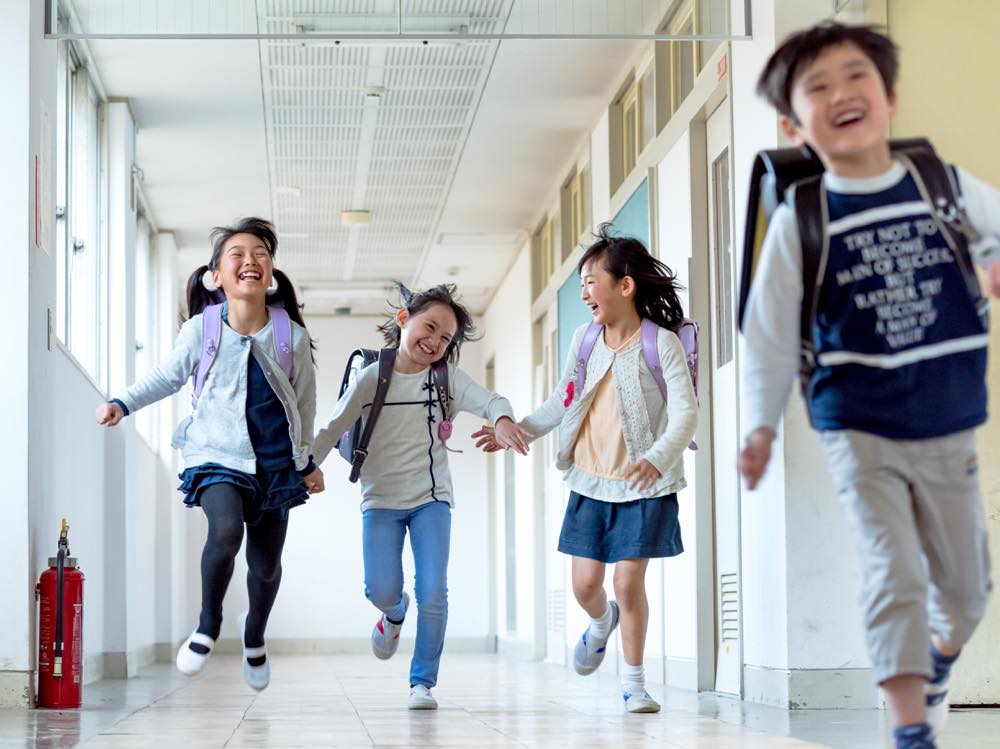 学校の廊下を笑顔で走る子どもたち